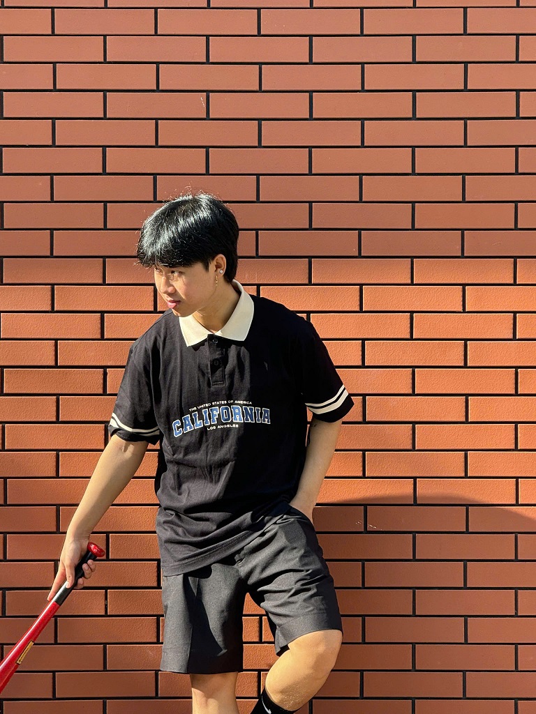 Một chàng trai trẻ trung mặc áo polo trắng phối cùng quần short kaki màu be và giày sneaker